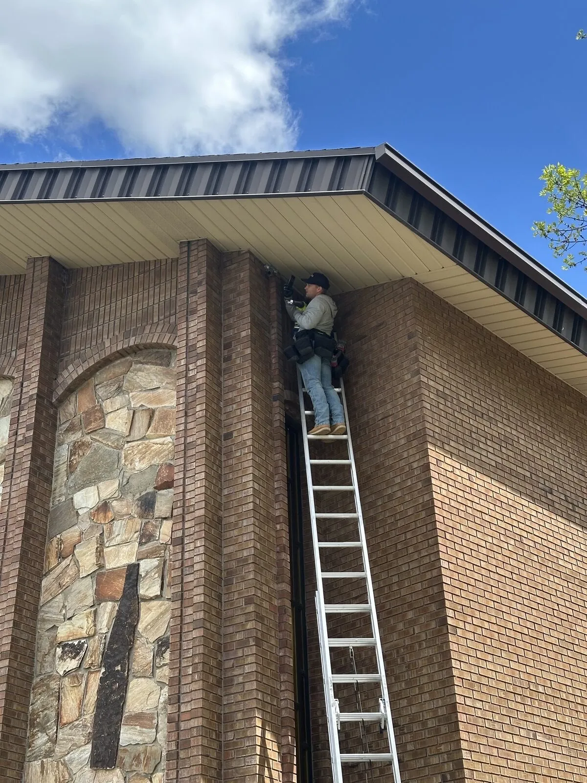 Technician on a ladder sealing a soffit at the eave line